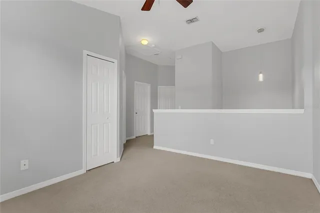 an empty room with a chandelier fan and windows