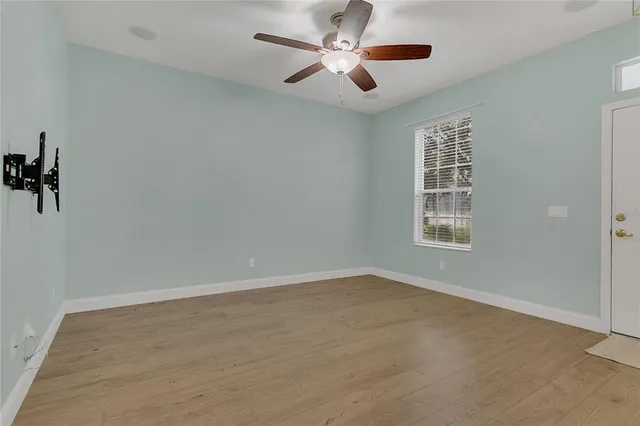 an empty room with a window and a ceiling fan