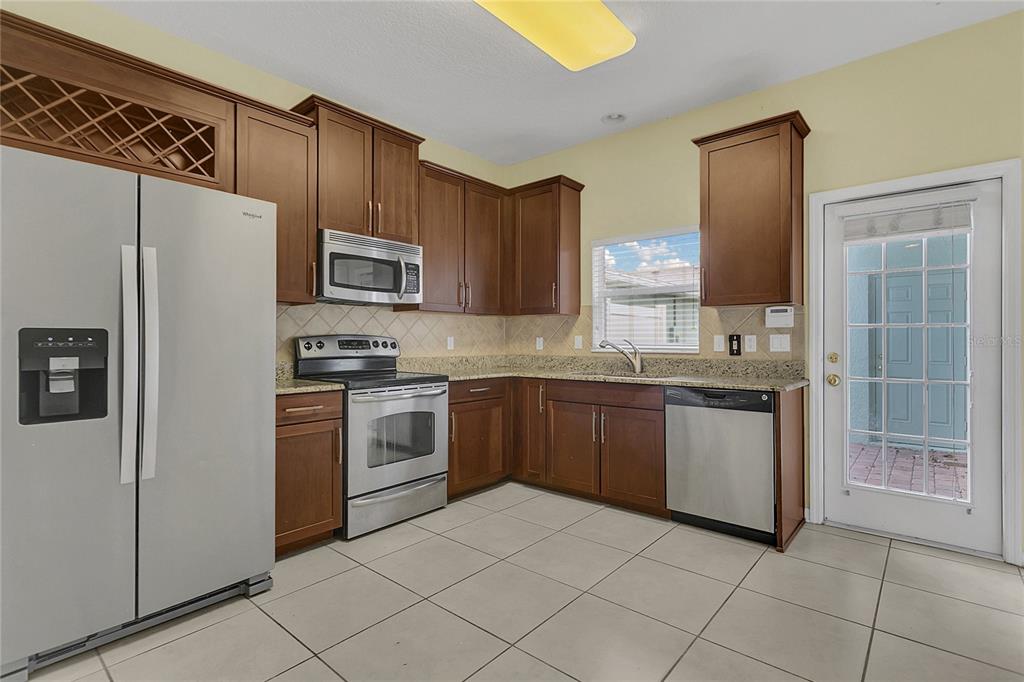 543 Rainbow Springs Loop Groveland, FL 34736 - Photo 9 of 26 a kitchen with granite countertop a refrigerator and a stove top oven