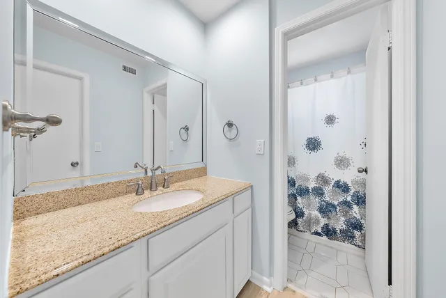 a bathroom with a granite countertop sink and a mirror