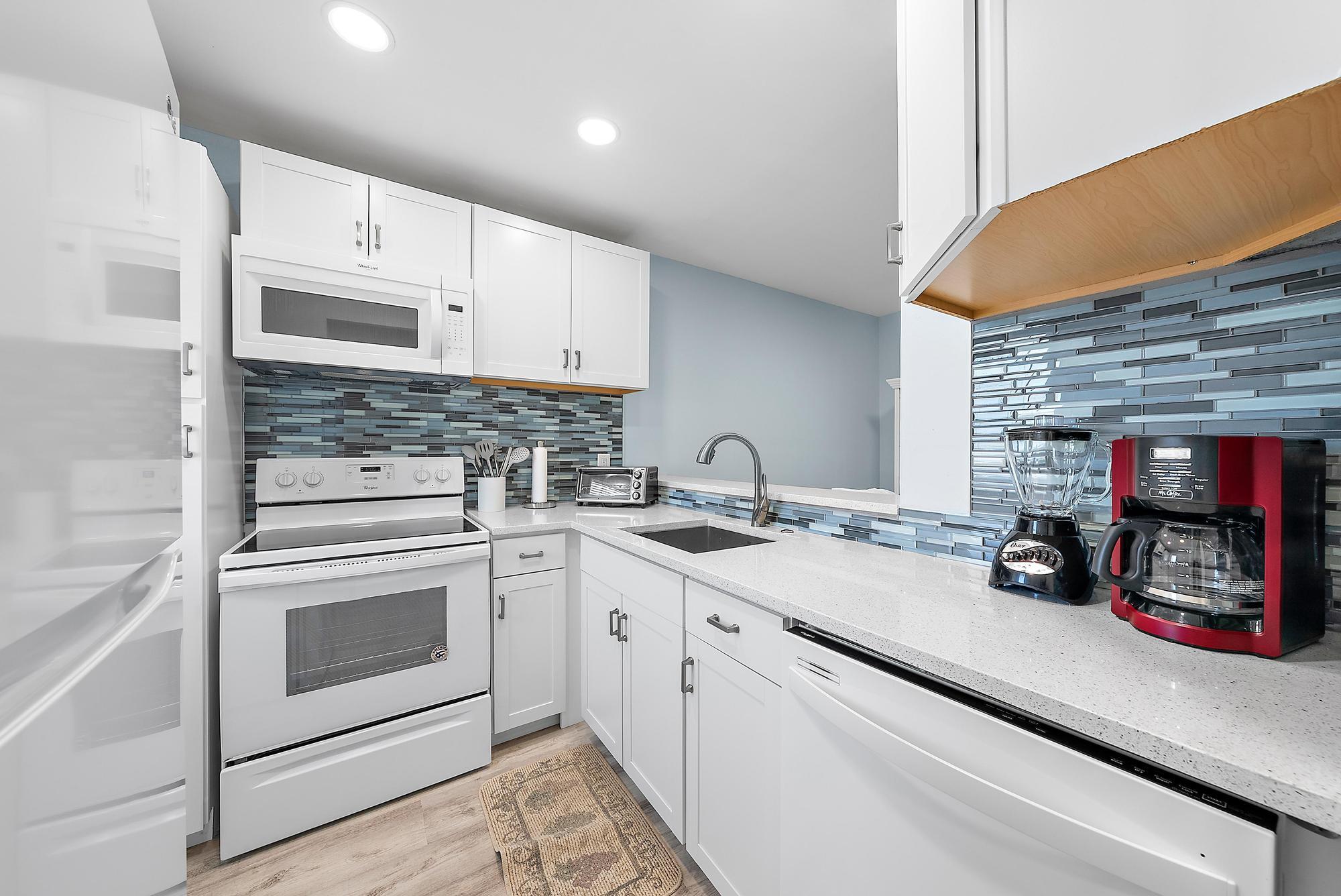 3851 North Ocean Boulevard, Unit 202 Gulf Stream, FL 33483 - Photo 6 of 20 a kitchen with stainless steel appliances granite countertop a sink stove and cabinets