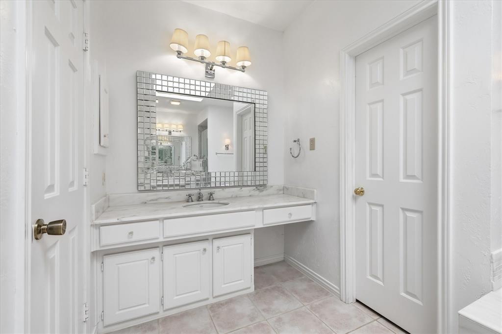 6955 Hawk Road Flower Mound, TX 75022 - Photo 23 of 40 Vanity area featuring a mosaic-framed mirror, four-light vanity fixture, white cabinetry with silver-tone hardware, and a built-in makeup vanity