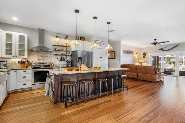 a kitchen with stainless steel appliances granite countertop a table chairs stove and refrigerator
