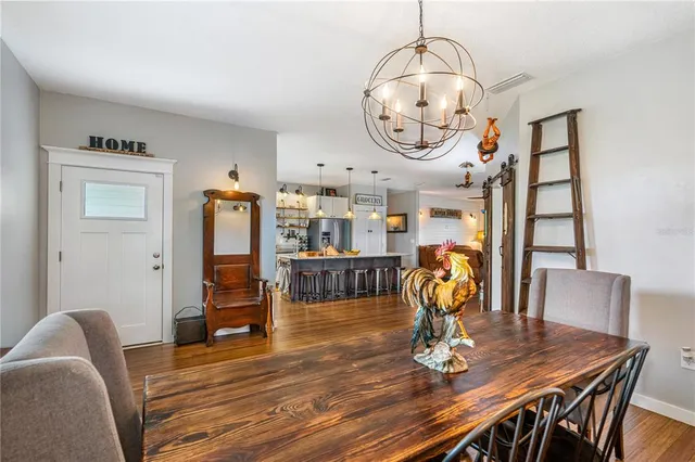 a kitchen with stainless steel appliances granite countertop a stove top oven a sink dishwasher a dining table and chairs with wooden floor