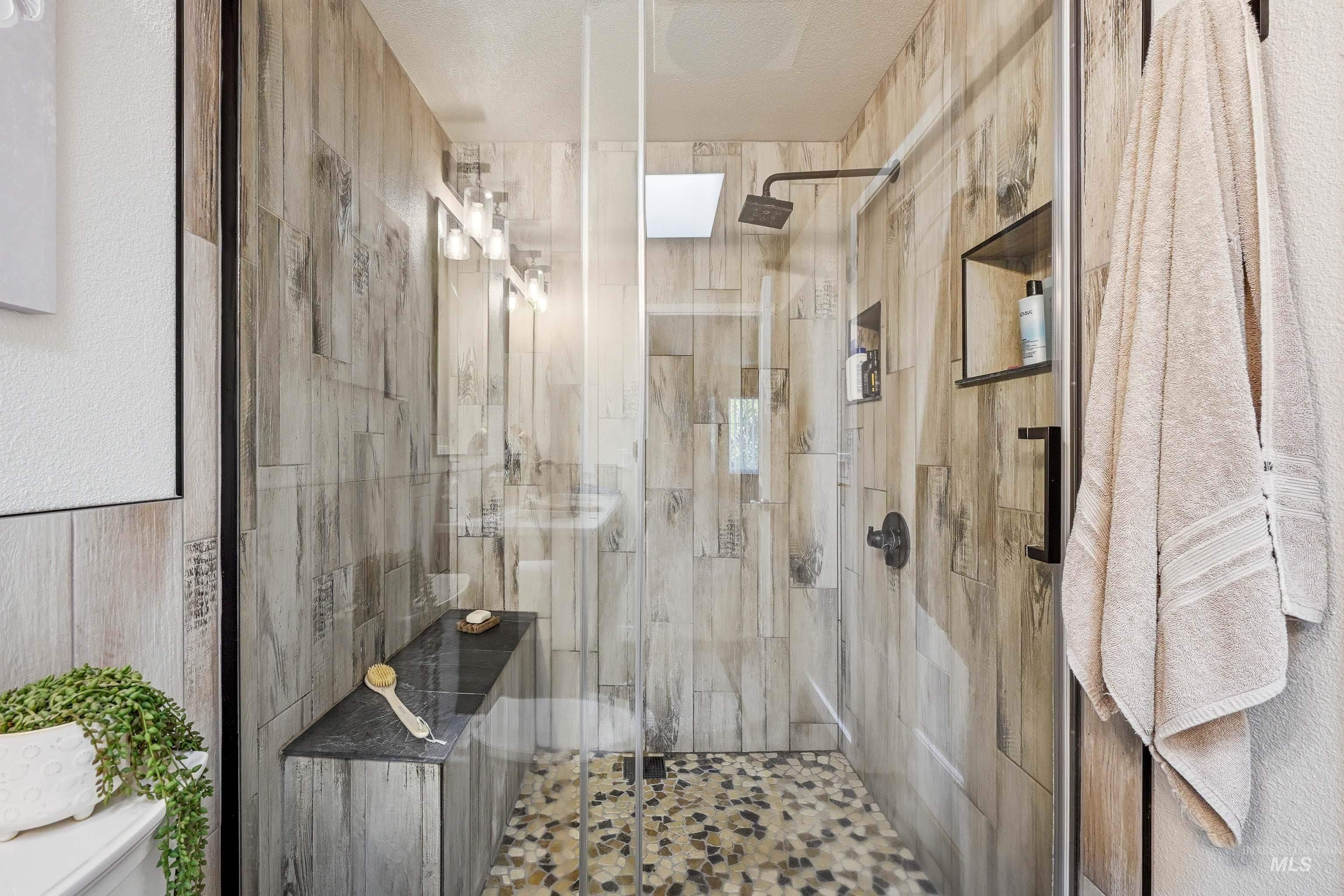 3715 18th Street Lewiston, ID 83501 - Photo 18 of 30 Walk-in shower with wood-look tile walls, pebble-style floor, built-in bench, recessed wall niche, and square rain shower head