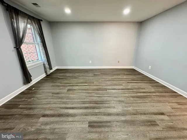 a view of empty room with window and wooden floor