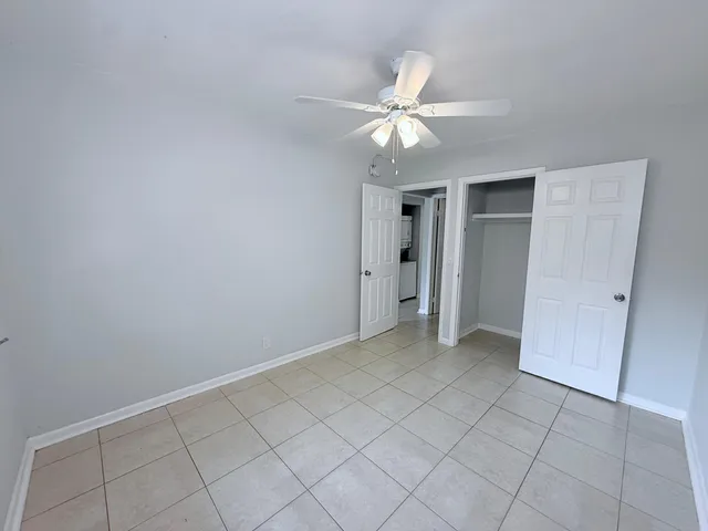 an empty room with closet and a chandelier fan