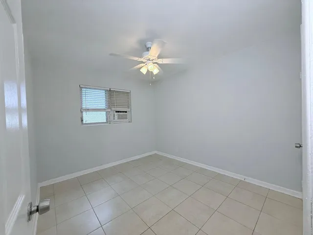 an empty room with a chandelier fan and windows