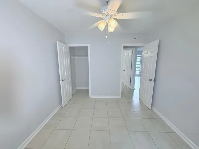 an empty room with closet and a chandelier fan
