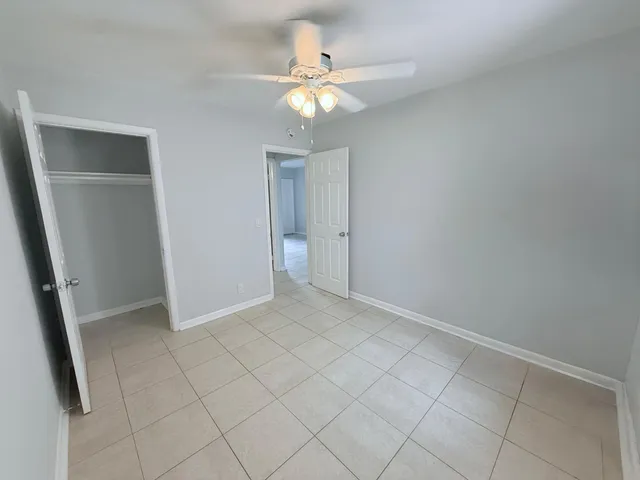 an empty room with closet and a chandelier fan