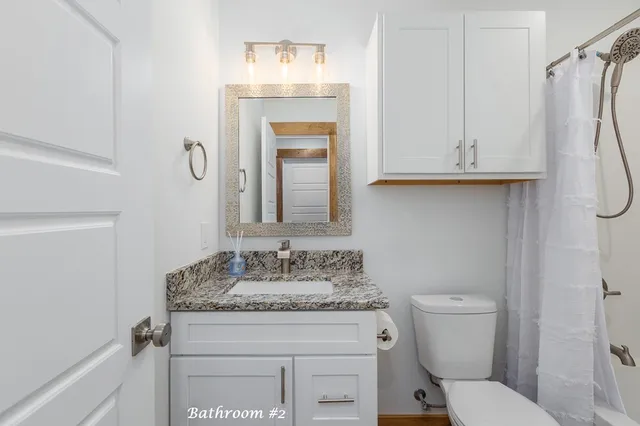 a bathroom with a granite countertop toilet sink and mirror