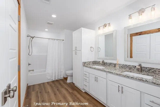 a spacious bathroom with a granite countertop sink a mirror and a shower