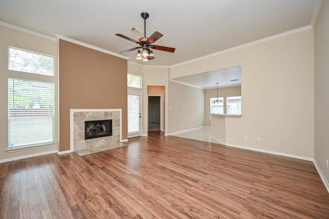 an empty room with wooden floor fireplace and windows