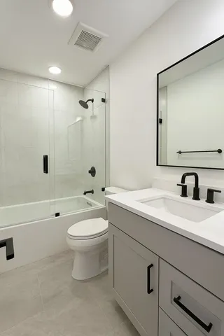 a bathroom with a toilet a sink a mirror a bathtub and vanity