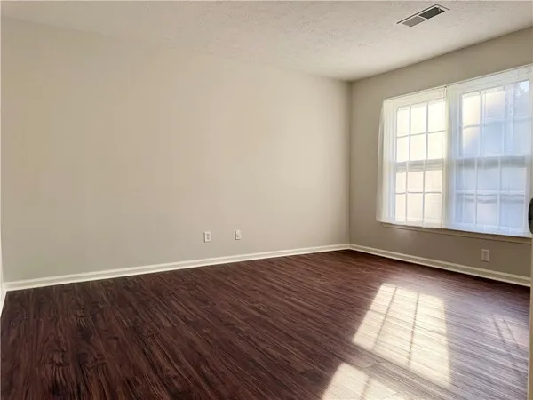 an empty room with wooden floor and windows