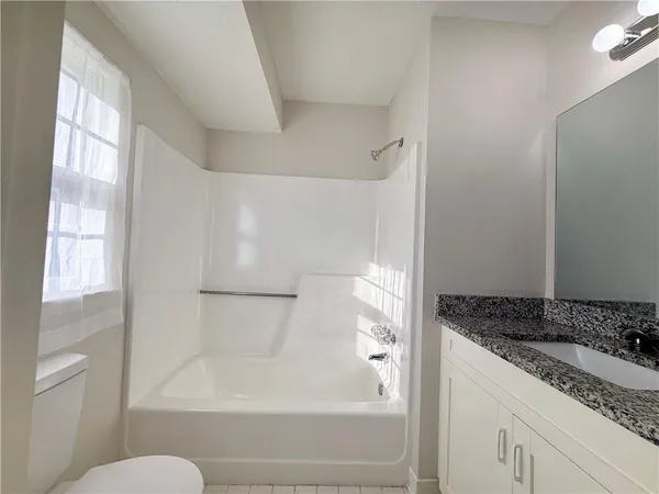 a bathroom with a granite countertop sink toilet and shower