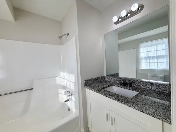 a bathroom with a granite countertop sink a large mirror and a bathtub