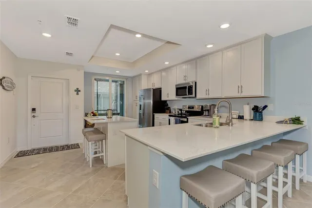 a kitchen with stainless steel appliances granite countertop a sink a stove a refrigerator cabinets and chairs