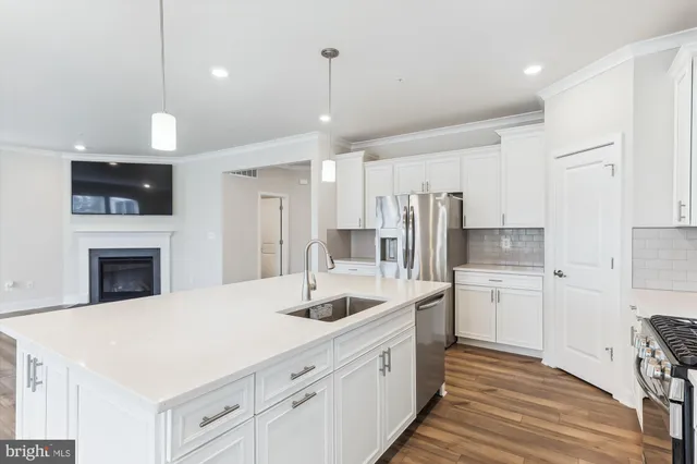 a kitchen with a white center island a sink cabinets and stainless steel appliances