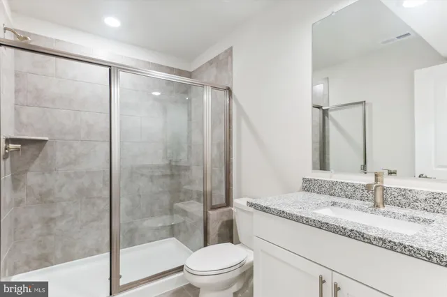 a bathroom with a granite countertop sink toilet and shower