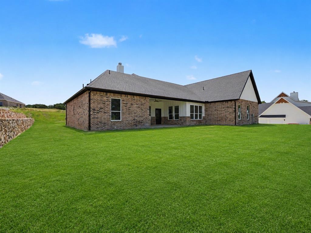 328 Slimp Bluff Azle, TX 76020 - Photo 30 of 30 Expansive rear lawn featuring a brick and siding exterior, covered patio, and dark shingle roof