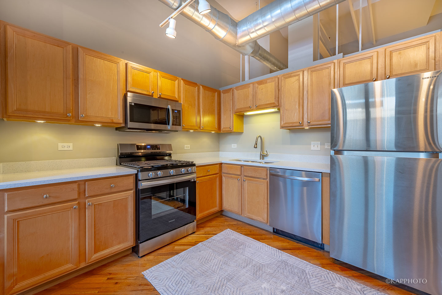 500 South Clinton Street, Unit 133 Chicago, IL 60607 - Photo 12 of 28 a kitchen with stainless steel appliances granite countertop a refrigerator a sink dishwasher a stove top oven a kitchen island and cabinets with wooden floor