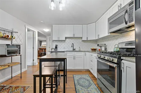 a kitchen with stainless steel appliances granite countertop a stove top oven a sink dishwasher and white cabinets