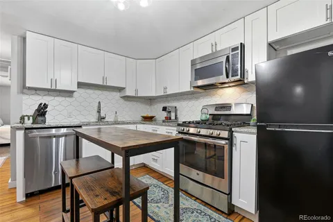 a kitchen with stainless steel appliances granite countertop a stove top oven a sink a table and chairs