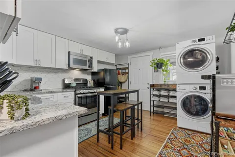 a kitchen with stainless steel appliances granite countertop a stove top oven a sink a dining table and chairs with wooden floor