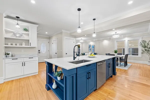 a large kitchen with cabinets a sink a center island and stainless steel appliances