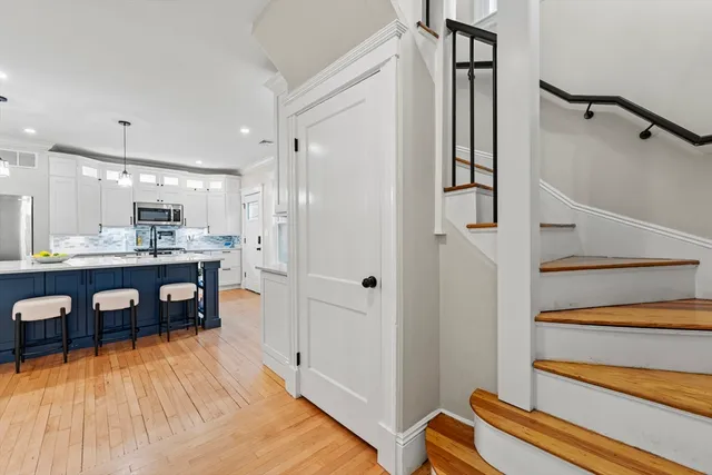 a kitchen with stainless steel appliances refrigerator wooden floor dining table and chairs