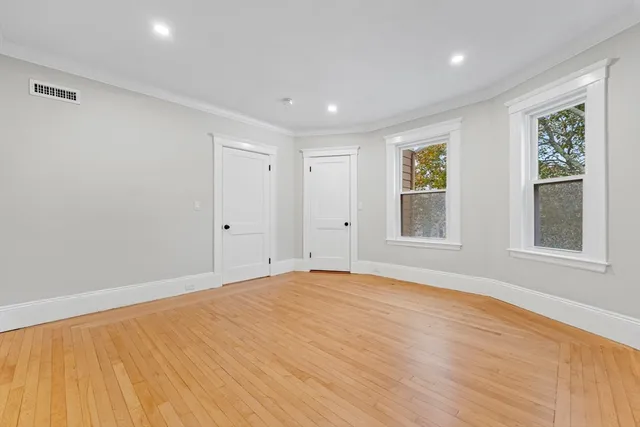 a view of empty room with wooden floor and fan