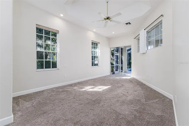 an empty room with windows and chandelier fan