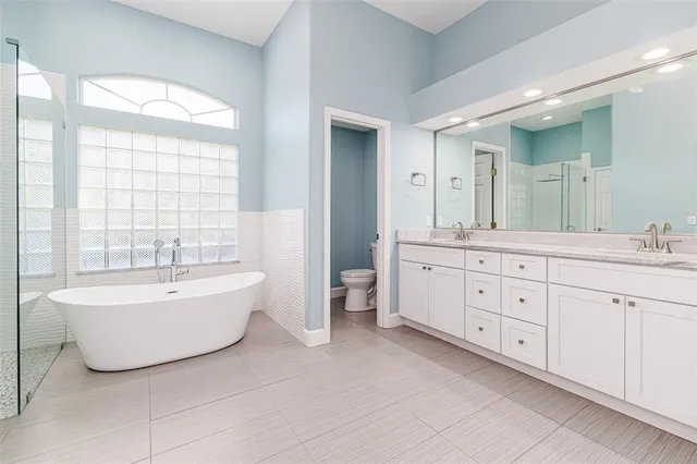 a spacious bathroom with double vanity a mirror a bathtub and a shower