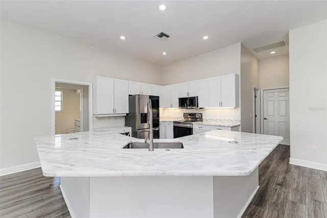 a kitchen with stainless steel appliances kitchen island granite countertop a sink and refrigerator
