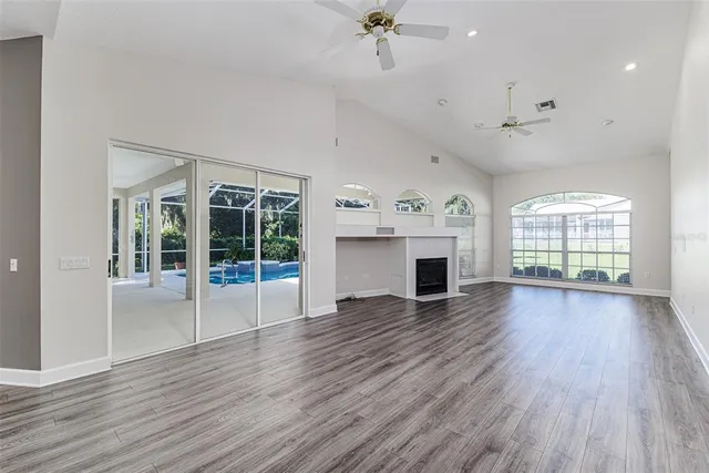 an empty room with wooden floor fireplace and windows