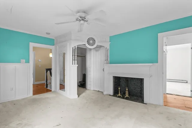 a view of a livingroom with a fireplace a ceiling fan and a refrigerator