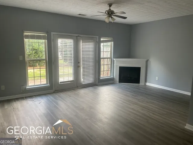 an empty room with windows fireplace and wooden floor