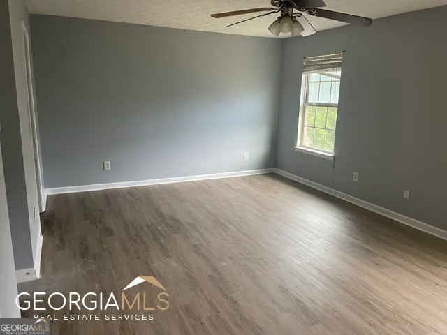 an empty room with a window and a ceiling fan