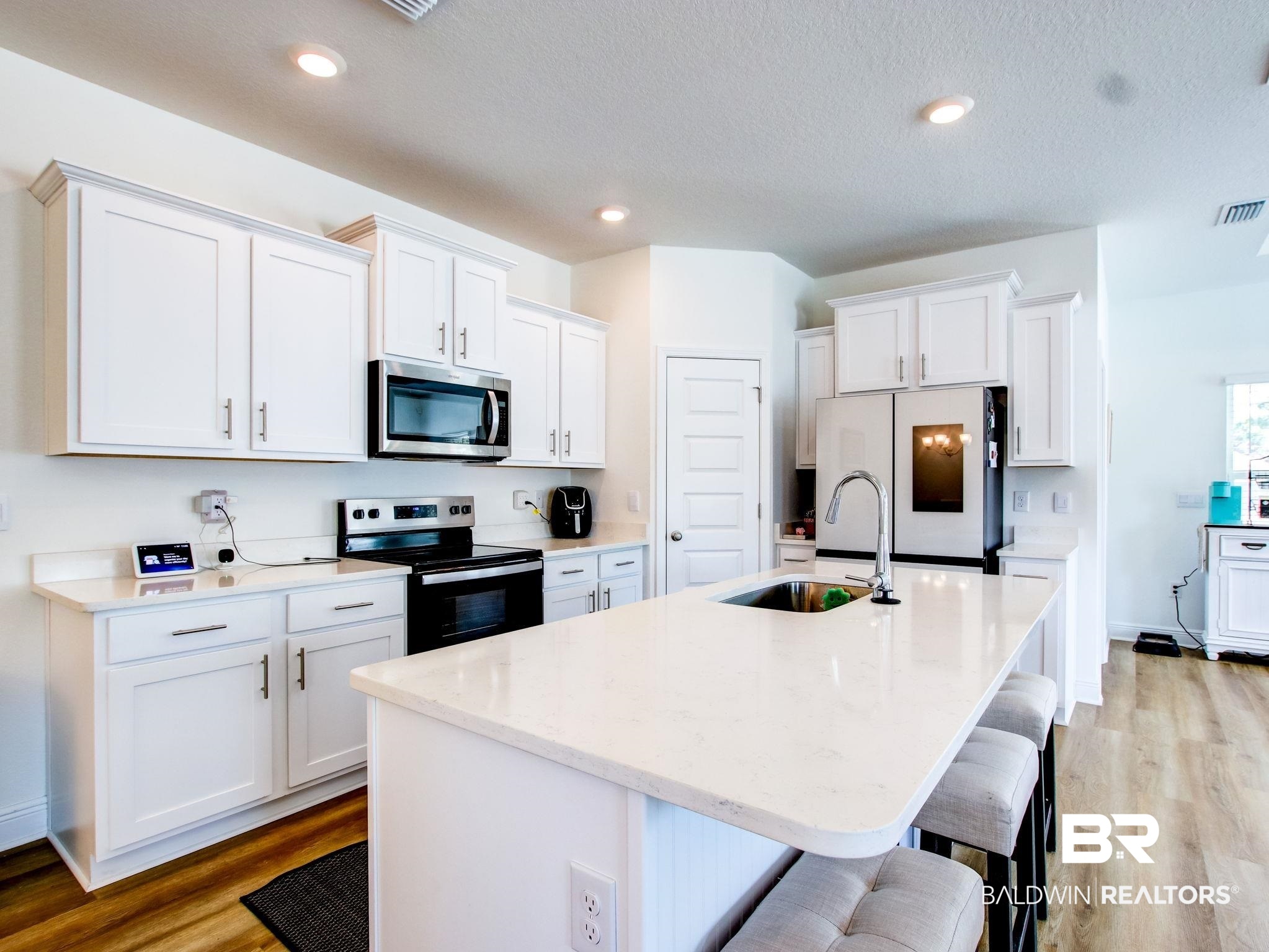 12919 Torrent Road Fairhope, AL 36532 - Photo 71 of 74 Kitchen featuring stainless steel appliances, white cabinets, a kitchen breakfast bar, light wood-type flooring, and a textured ceiling