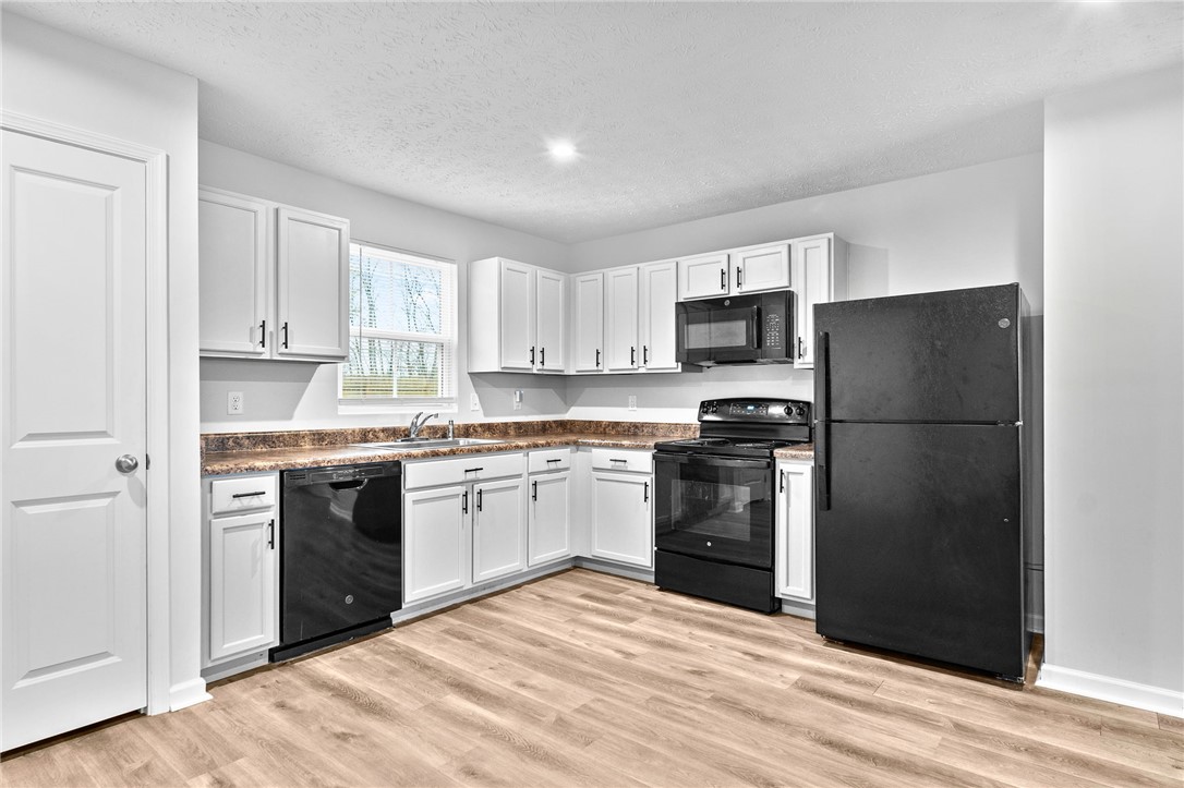 226 Golden Gate Avenue Springfield, OH 45506 - Photo 6 of 20 This modern kitchen features crisp white cabinetry and dark appliances, ready for culinary creations.