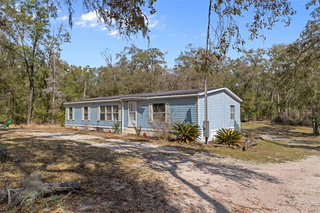 a front view of house with yard and trees in the background