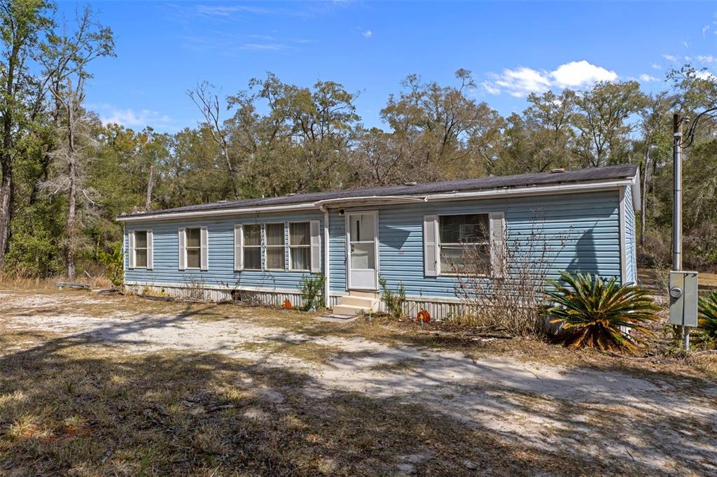 11881 Southwest 45th Street Webster, FL 33597 - Photo 5 of 27 a front view of house with yard and trees in the background