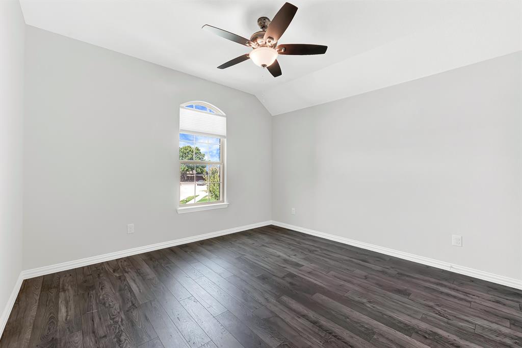 7640 Rhyner Way Fort Worth, TX 76137 - Photo 32 of 40 Bright corner bedroom showcasing dark wood-finish flooring, clean white walls, and abundant natural light from an arched window