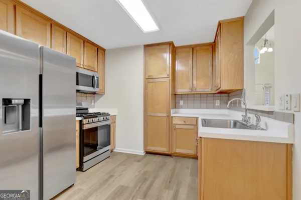 a kitchen with stainless steel appliances granite countertop a refrigerator a stove a sink and a microwave