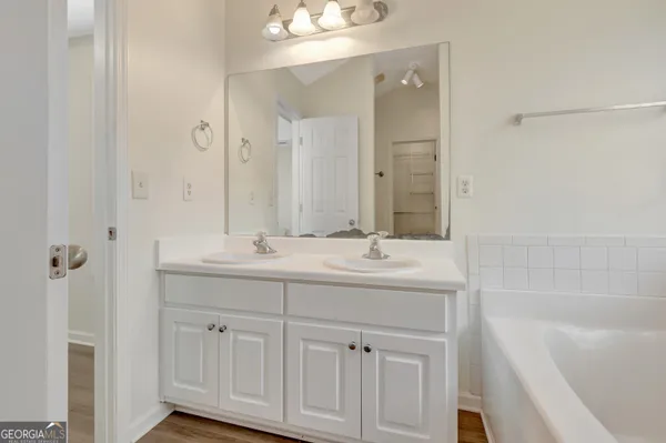 a bathroom with a double vanity sink a mirror and a bathtub