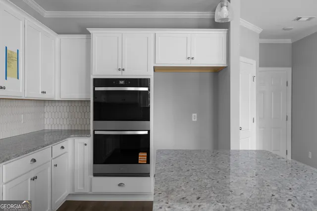 a kitchen with granite countertop white cabinets and stainless steel appliances