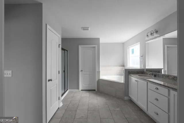 a bathroom with a granite countertop sink a mirror and a bathtub
