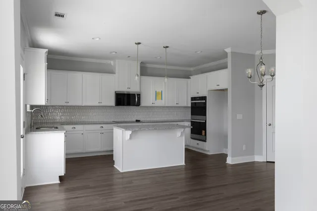 a kitchen with stainless steel appliances granite countertop a refrigerator a sink dishwasher a stove and white cabinets with wooden floor