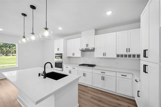 a kitchen with white cabinets a sink dishwasher and white appliances with wooden floor